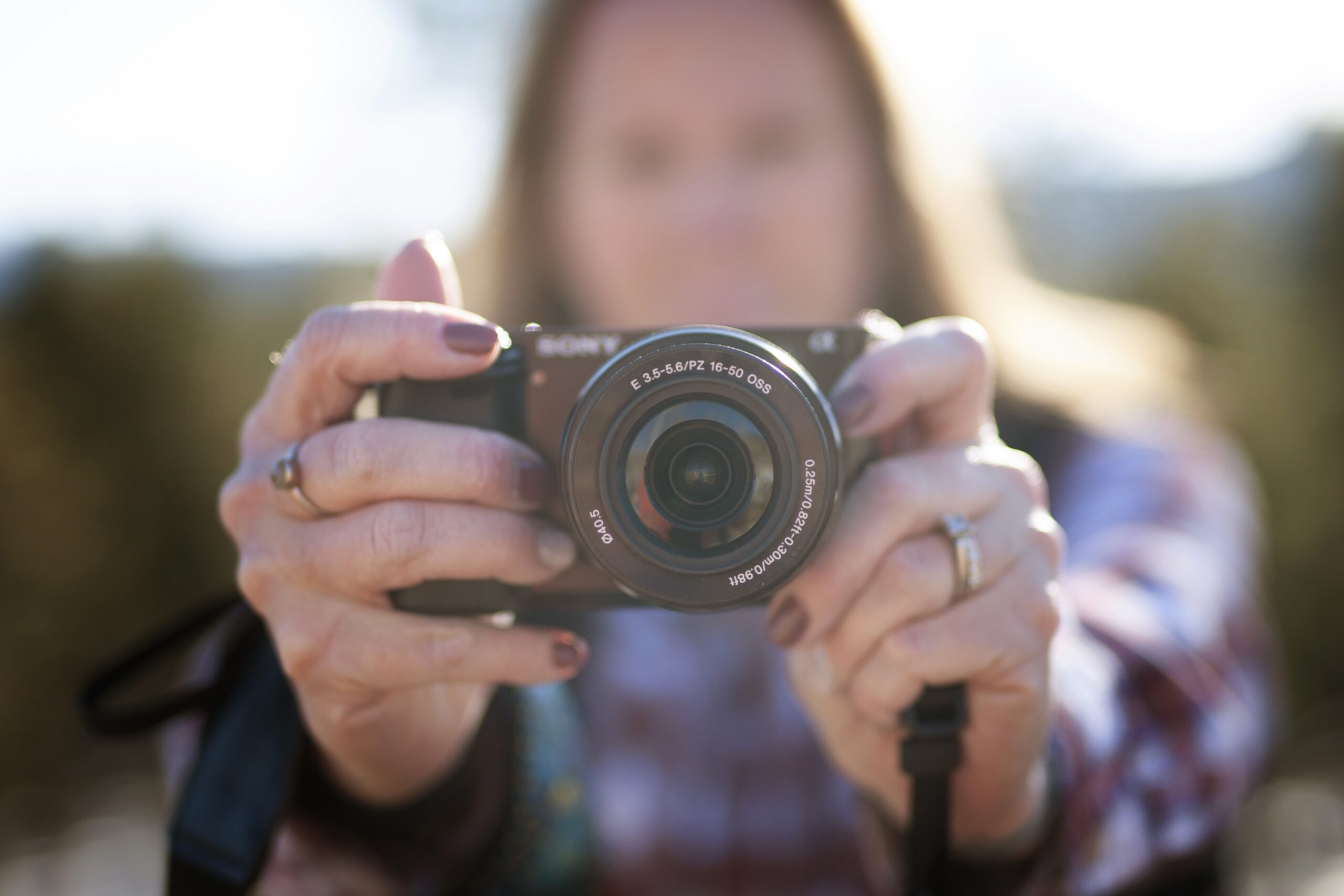A blurry person in the background holding a camera up which is in focus